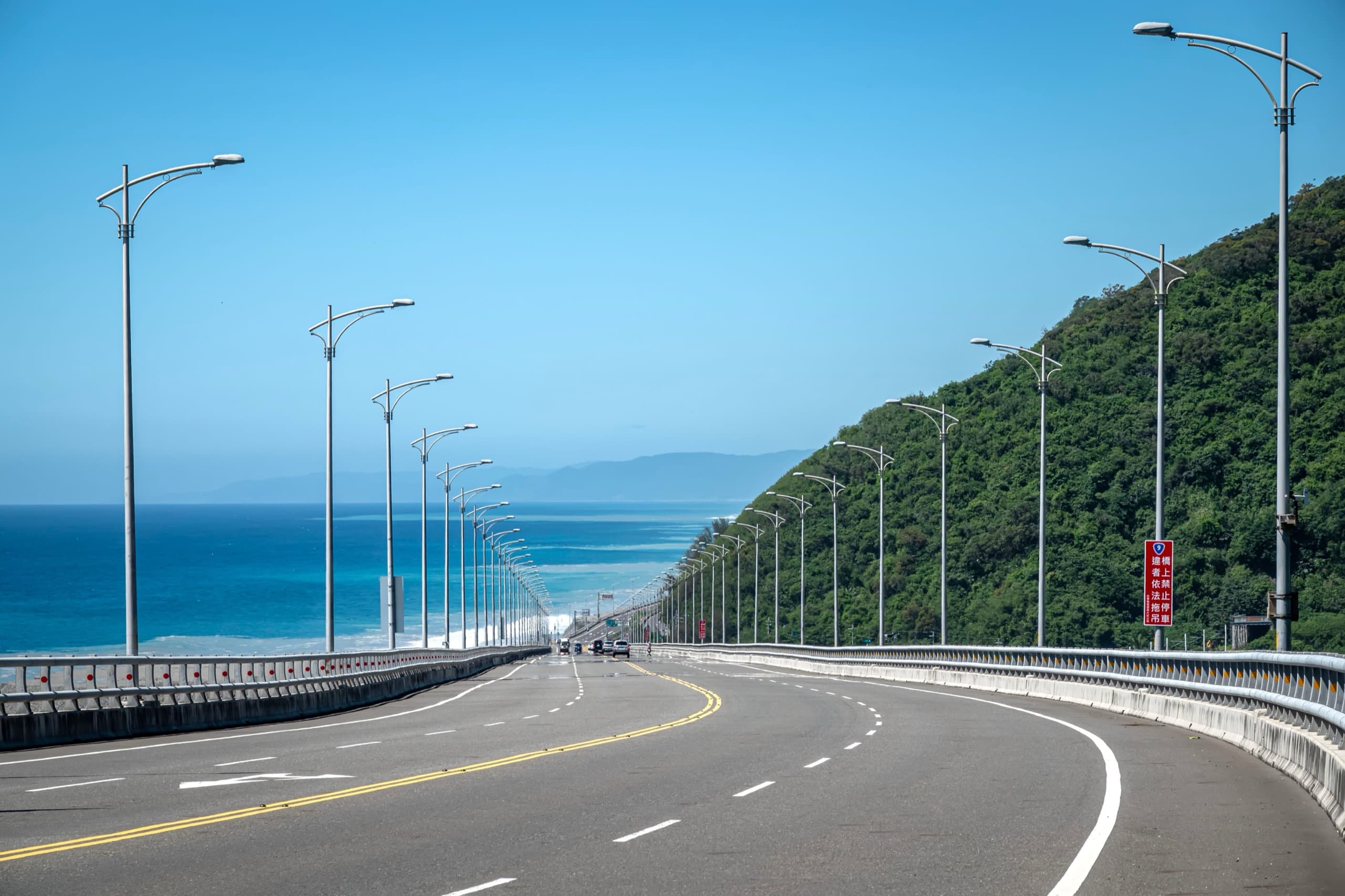 濱海公路沿著山腳往前延伸，左邊是深藍色的海