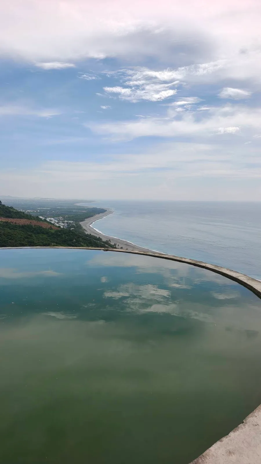 圓形蓄水池的水面映著雲，外面接著海岸（實景・五星台東旅遊自攝）
